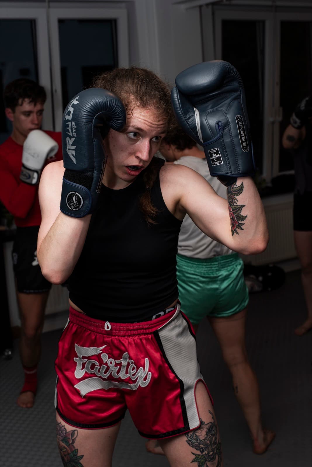 Anna in Kampfhaltung mit Handschuhen am Kinn im Trainingsraum